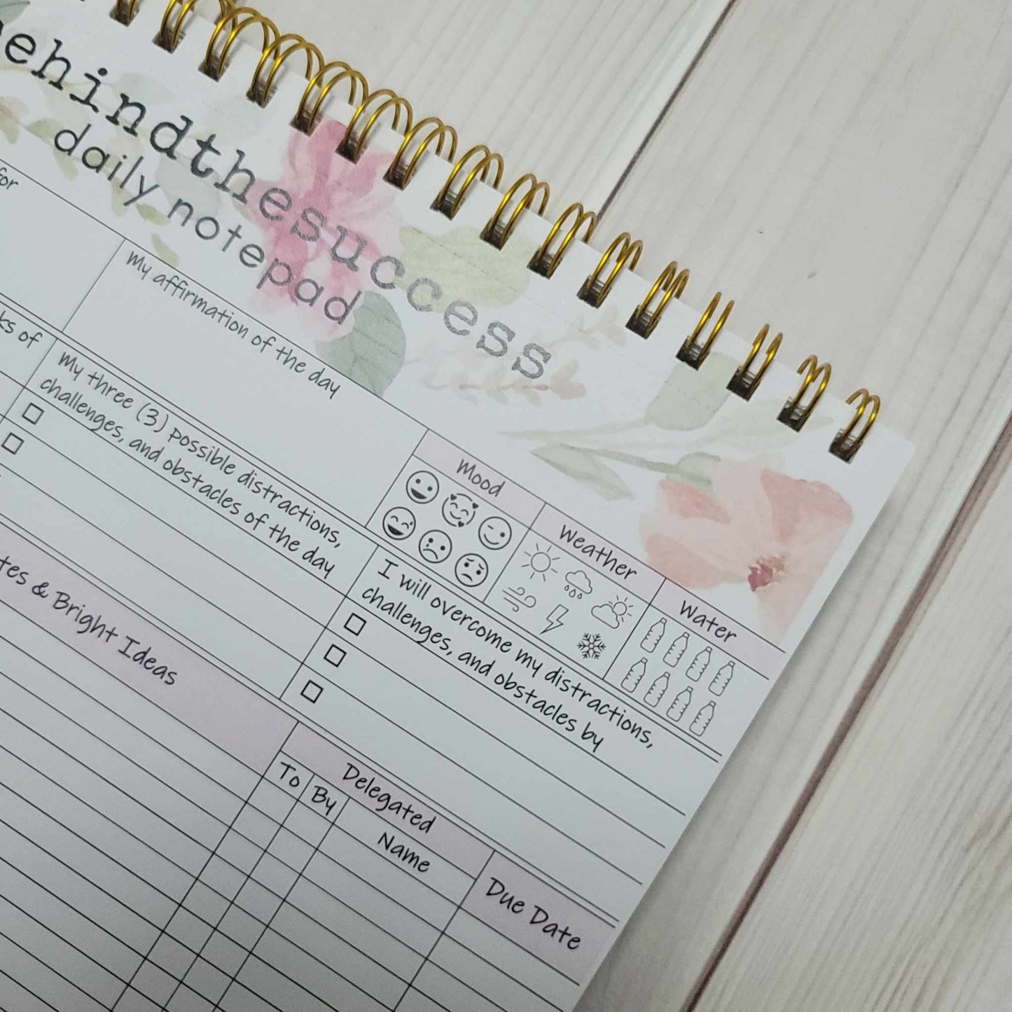 Floral spiral undated daily planner page with mood, weather, and water tracker sections.