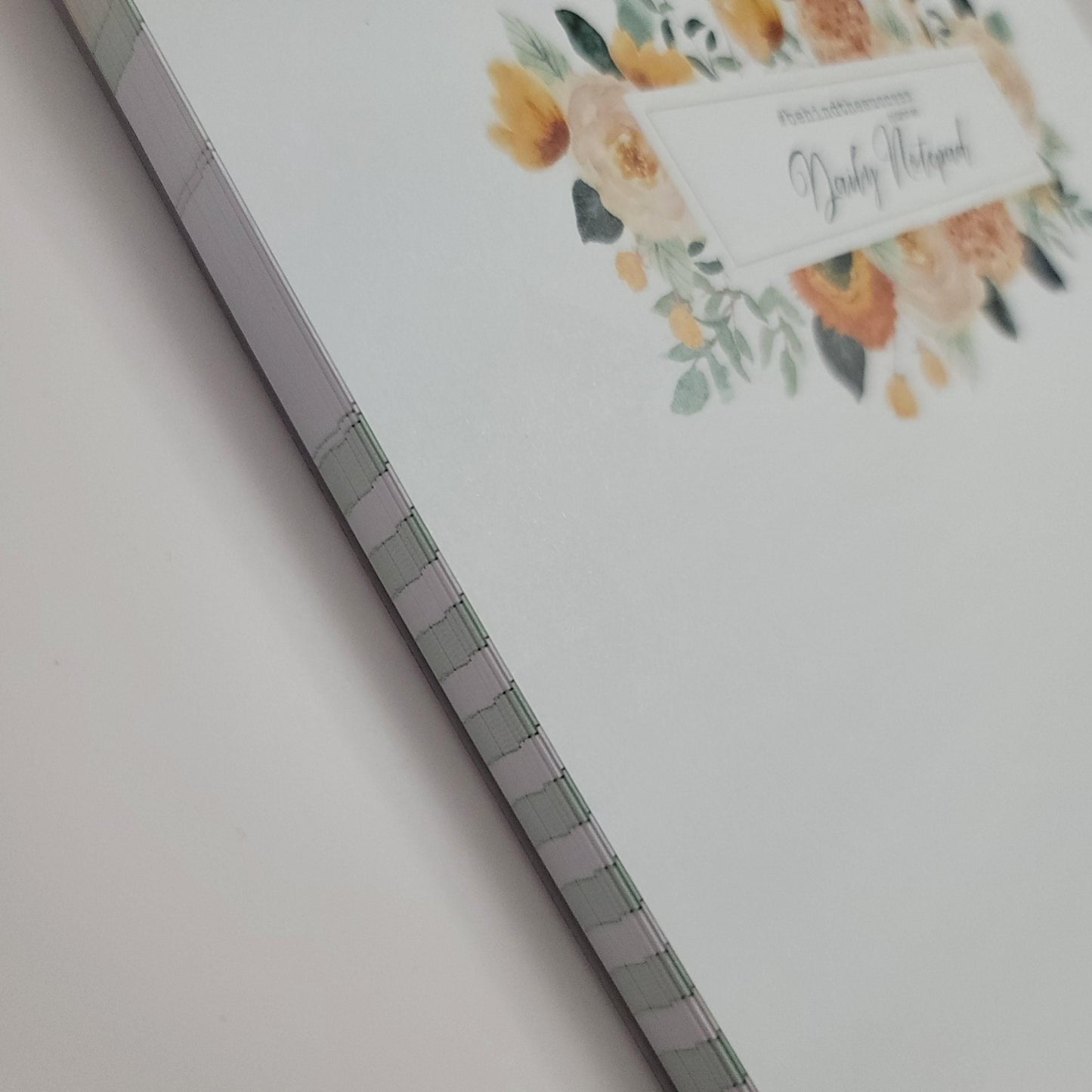 Undated daily notepad with floral cover, stitched binding, white background