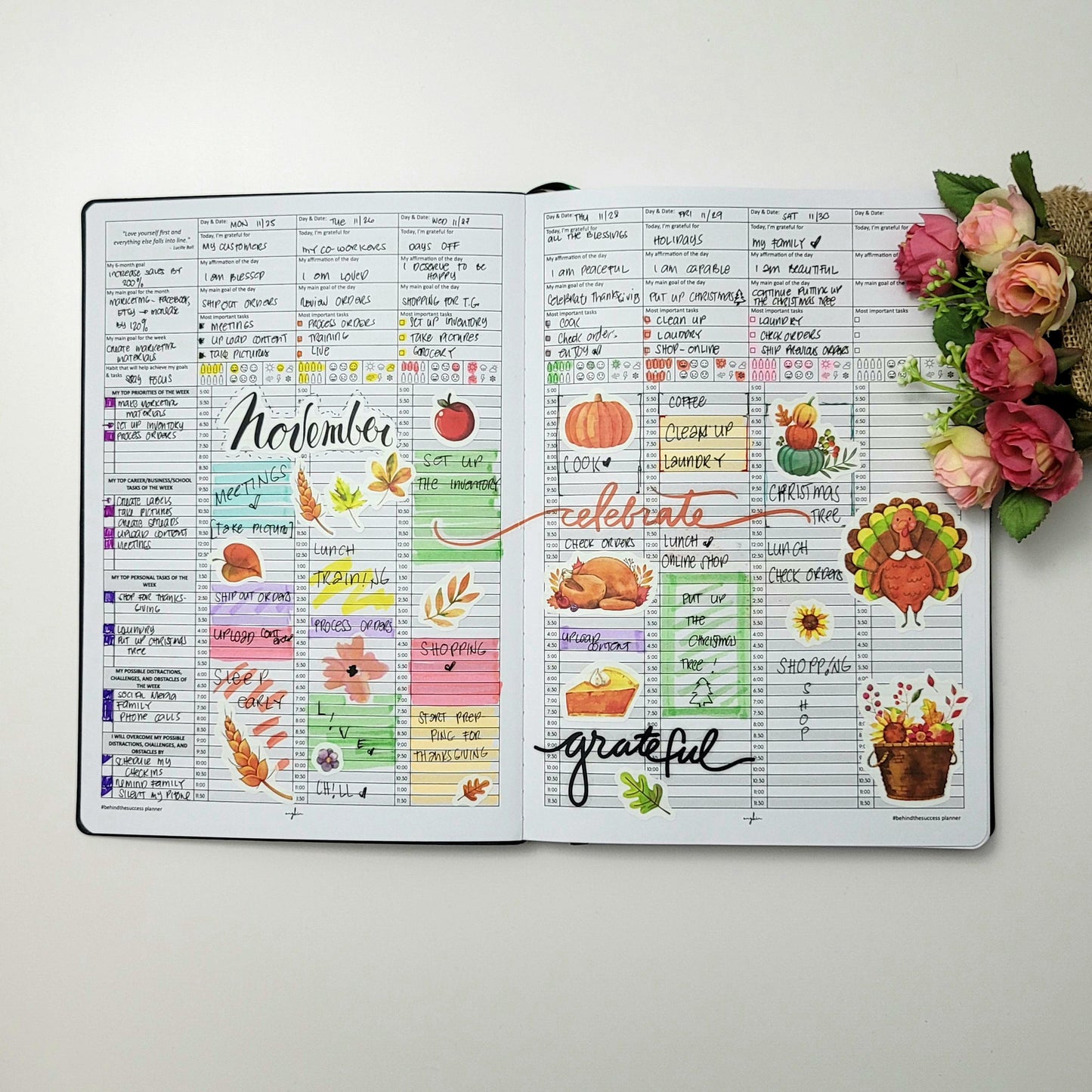 Open undated life planner with colorful November layouts, stickers, and flowers beside