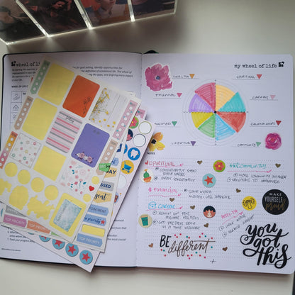 Open productivity life planner with colorful stickers and wheel of life chart on desk