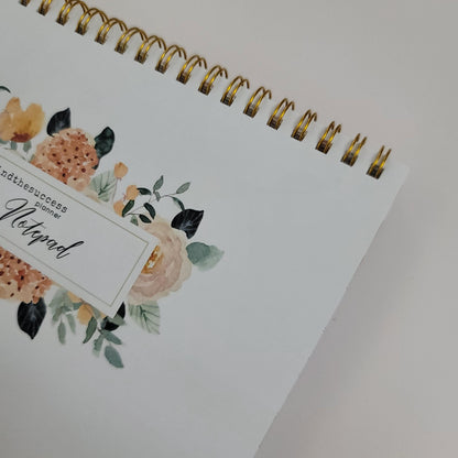 Spiral-bound floral notepad with gold ring binding and elegant flower design on cover