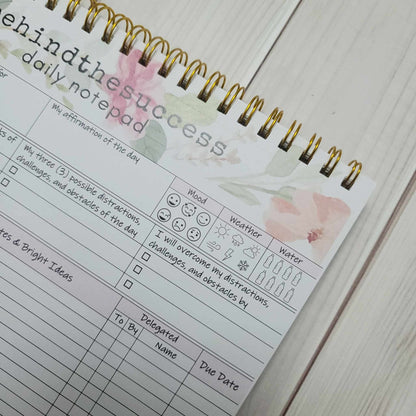 Floral spiral undated daily planner page with mood, weather, and water tracker sections.