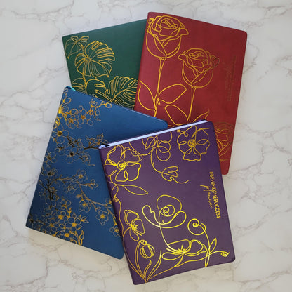 Colorful floral-embossed planners with gold foil on marble background, productivity journals